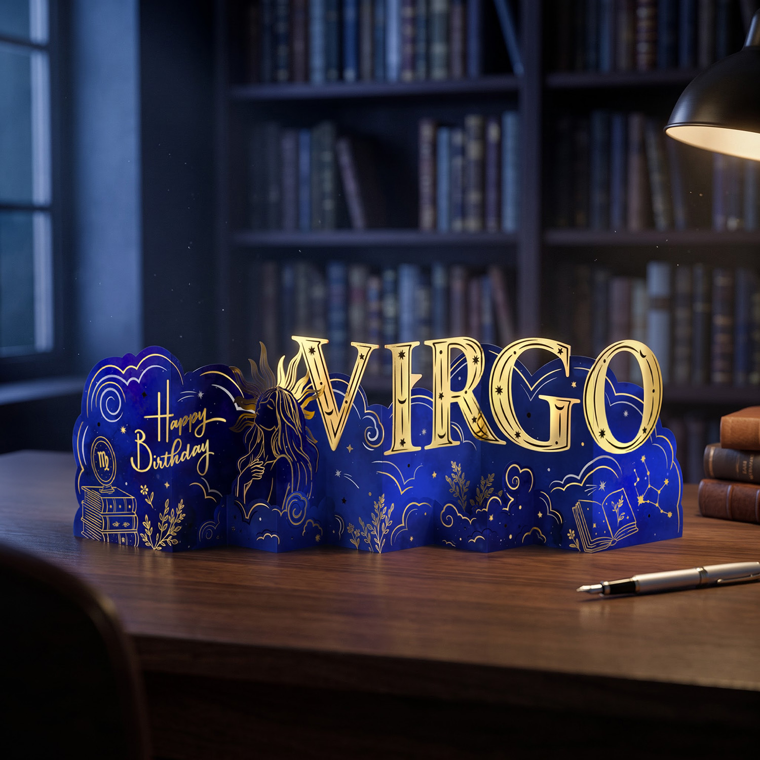 Gold foil zodiac birthday card standing open on a desk under a lamp